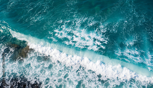 From above aerial view of turquoise ocean water with splashes and foam for abstract natural background and texture