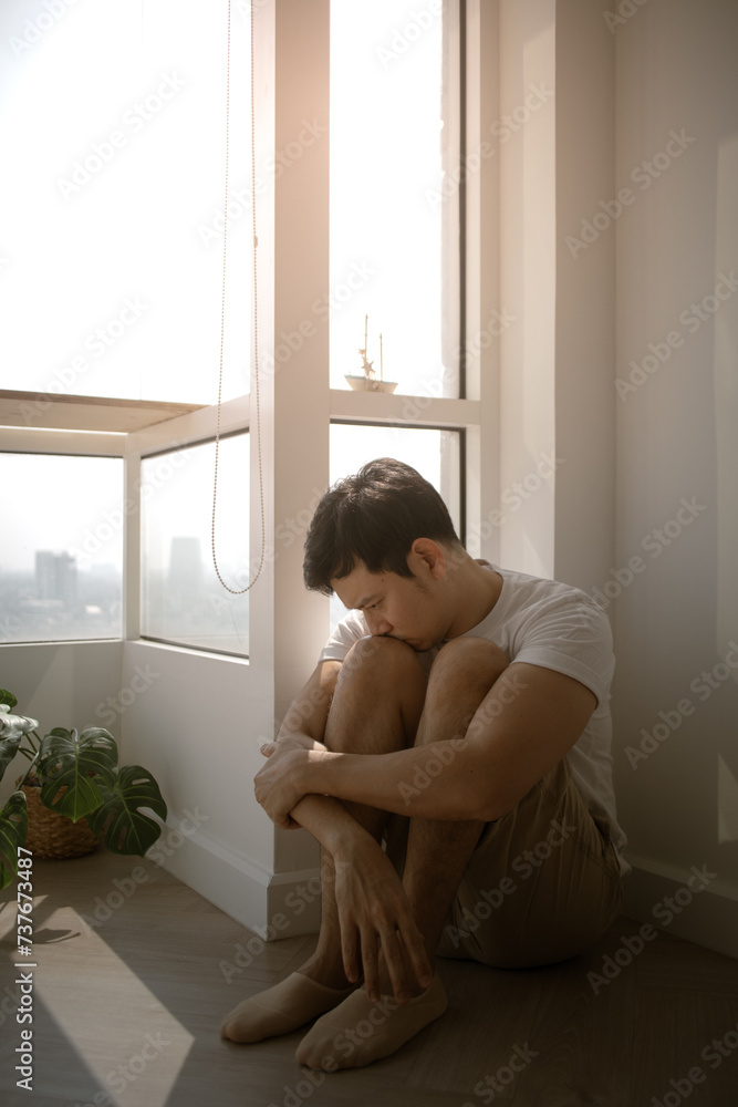 Sad and lonely Asian man sits on the floor hugging his knee. Sad and lonely Asian man sits on the floor hugging his knee.