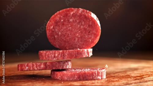 Pieces of salami fall onto a wooden board. Filmed on a high-speed camera at 1000 fps. High quality FullHD footage photo