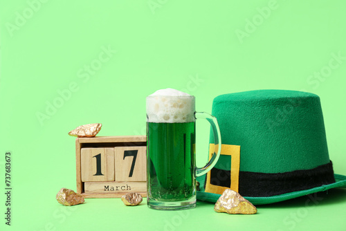 Cube calendar with date 17 MARCH, glass of beer and leprechaun hat on green background. St. Patrick's Day celebration