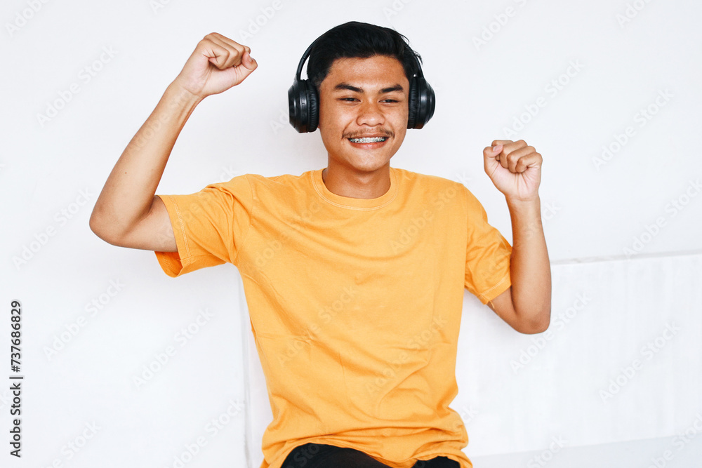 Φωτογραφία Happy Asian teenage boy wearing headphones listening music and dancing