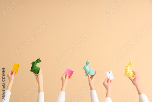Women with credit cards and Easter rabbits on beige background. Online shopping