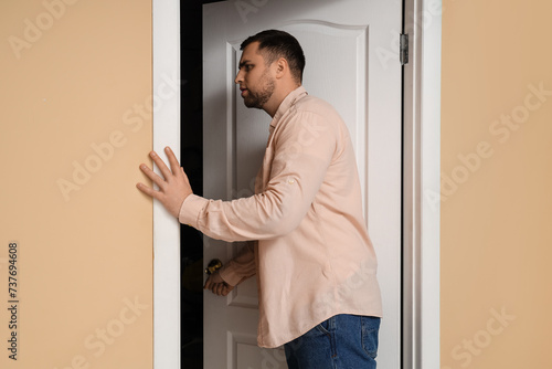 Young man looking through open door in room