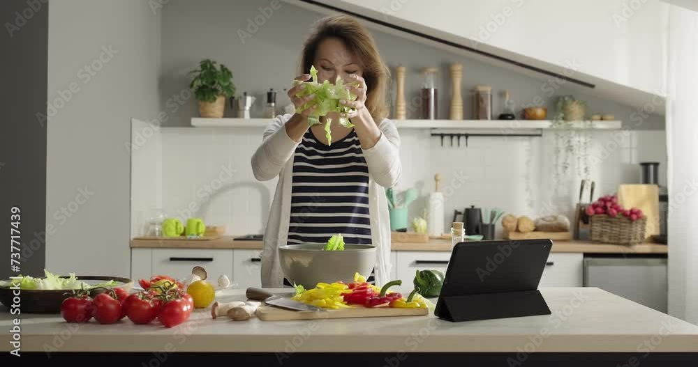 Happy smiling woman prepares salad at home, fills a bowl with iceberg lettuce. Homemade food. Healthy proper nutrition lifestyle Happy smiling woman prepares salad at home, fills a bowl with iceberg lettuce. Homemade food. Healthy proper nutrition lifestyle