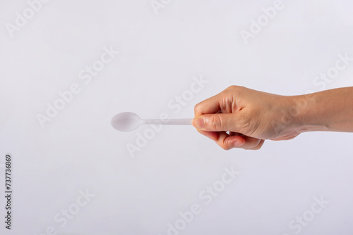 White plastic spoon in hand on white background