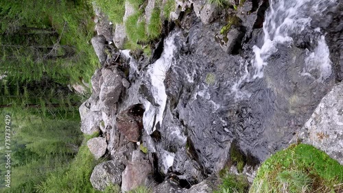 mountain creek in the Alps is flowing down along a stony riverbed photo