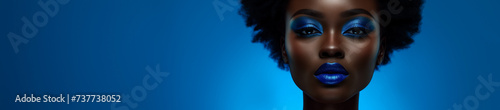 African American woman with vibrant blue makeup against a blue background with ample copy space on the left