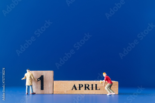 Miniature people painting a wooden block on April 1st, April fools day concept photo