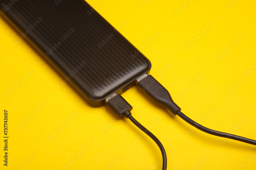 External battery power bank with usb cables on yellow background External battery power bank with usb cables on yellow background