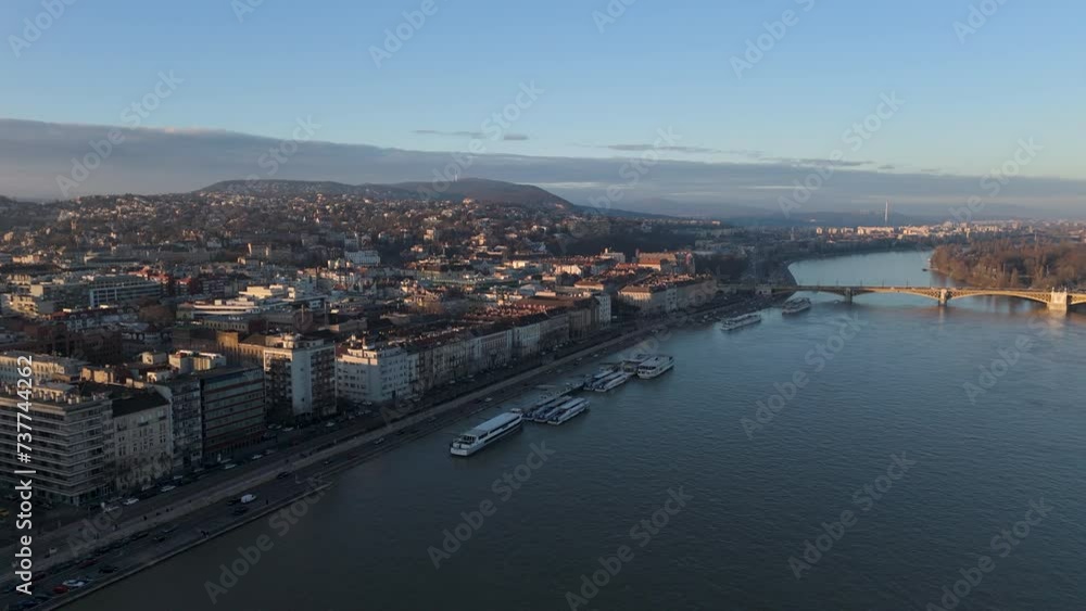 Top view of the wide long river with sailing and moored ships and boats at dawn, cityscape on the bank of the river with plenty of high buildings, road. High quality 4k footage Top view of the wide long river with sailing and moored ships and boats at dawn, cityscape on the bank of the river with plenty of high buildings, road. High quality 4k footage
