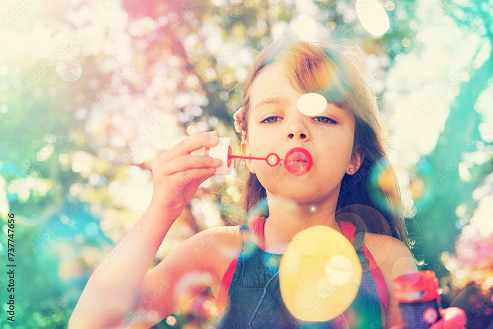 Portrait, nature and kid blowing bubbles at park, relax and girl having fun outdoor. Toy, garden and face of child with soap on summer vacation for recreation, leisure and playing game in low angle