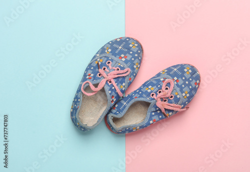 Children's used sneakers on pink blue background