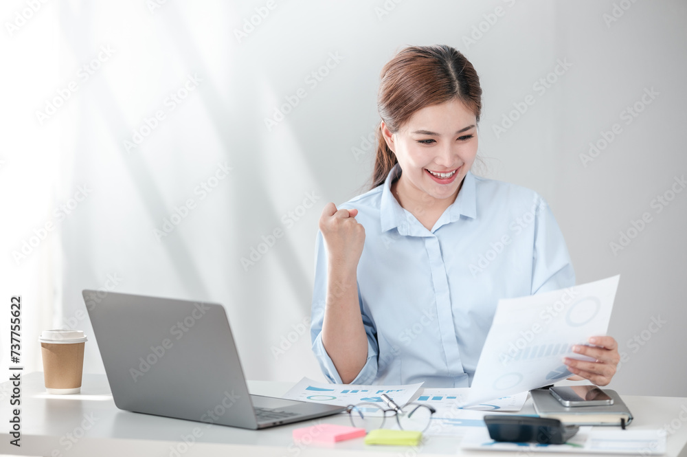 Cheerful Successful Asian Business woman using calculator and laptop for doing math finance on an office desk, tax, report, accounting, statistics, and analytical research concept Cheerful Successful Asian Business woman using calculator and laptop for doing math finance on an office desk, tax, report, accounting, statistics, and analytical research concept
