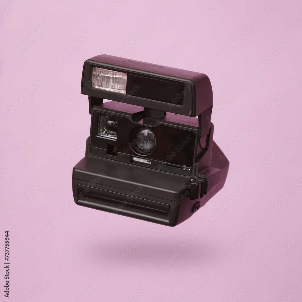 Levitating retro camera levitating on pink background with shadow Levitating retro camera levitating on pink background with shadow