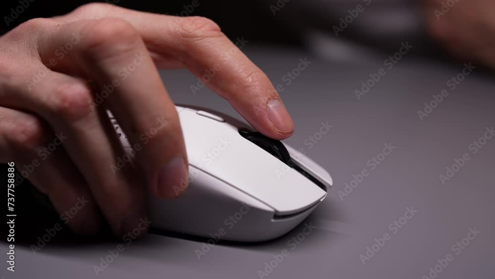 Close-up cropped shot of unrecognizable man using wireless computer mouse, scrolling through apps and websites with wheel and clicks on buttons, sitting at desk in dark room with cozy light. Close-up cropped shot of unrecognizable man using wireless computer mouse, scrolling through apps and websites with wheel and clicks on buttons, sitting at desk in dark room with cozy light.