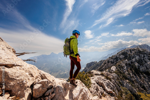 A girl with a backpack on a hike. adventure in the mountains. hiking with a backpack. girl with a backpack in the high mountains. Rock climbing and mountaineering concept.