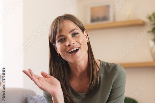 A middle-aged Caucasian woman gestures on a video call, cheerful in a home setting