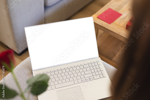 A laptop with a white screen is open on a wooden table, with copy space