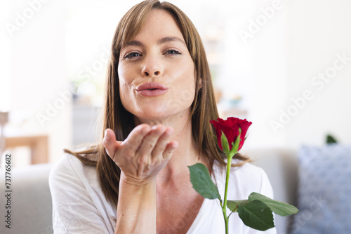 A Caucasian woman appears to be in a cheerful mood as she blows a kiss towards the camera  holding a