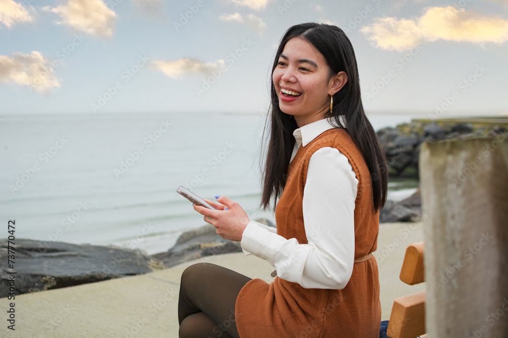 Young pretty asian woman texting on her phone Young pretty asian woman texting on her phone
