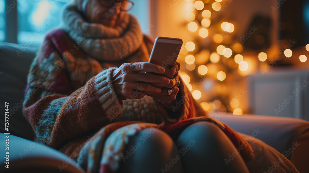 elderly woman uses a smartphone to browse social media and communicate with friends and family. In a cozy living room with soft lighting - obrazy, fototapety, plakaty 
