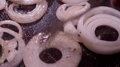 Fresh raw onion rings sputter in hot oil skillet on stovetop photo