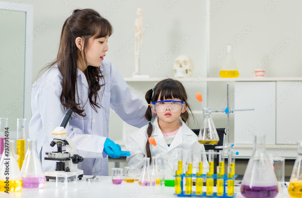 Asian woman teacher and little children girl making science experiments tests in chemical laboratory study room. Education research and development concept learning for kids. Asian woman teacher and little children girl making science experiments tests in chemical laboratory study room. Education research and development concept learning for kids.