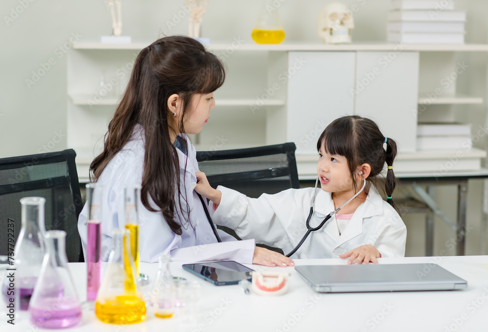 Asian woman doctor and cheerful little girl applying medical stethoscope at doctor appointments in laboratory lab. Education healthcare, medicine childrens hospital concept learning for kids Asian woman doctor and cheerful little girl applying medical stethoscope at doctor appointments in laboratory lab. Education healthcare, medicine childrens hospital concept learning for kids