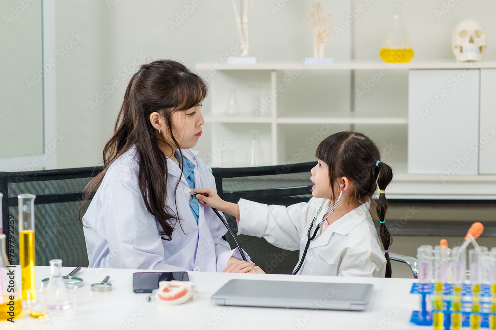 Asian woman doctor and cheerful little girl applying medical stethoscope at doctor appointments in laboratory lab. Education healthcare, medicine childrens hospital concept learning for kids Asian woman doctor and cheerful little girl applying medical stethoscope at doctor appointments in laboratory lab. Education healthcare, medicine childrens hospital concept learning for kids