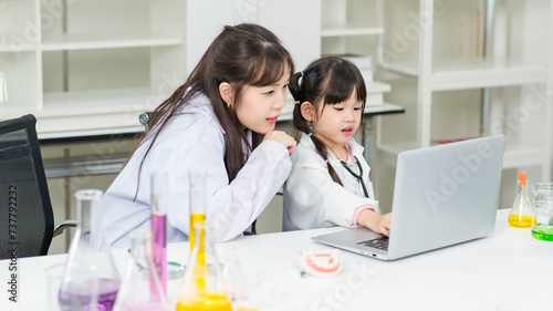Asian woman teacher and little children girl reading laptop computer for data learning science at chemical laboratory study room. Education research and development concept learning for kids. © Bangkok Click Studio