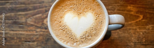 Cup of coffee with heart shape foam on wooden table background. Banner.