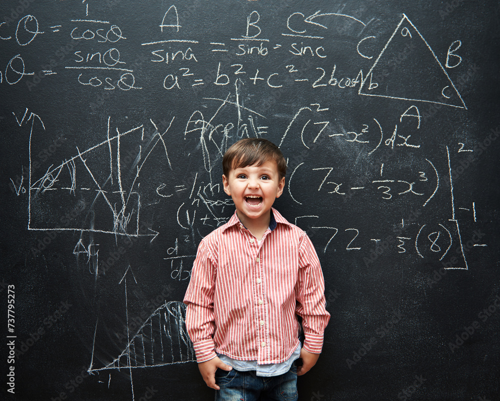 Child, boy and face or excited by blackboard with letters, numbers and education in classroom at school. Kid, student and happy for knowledge, learning and chalkboard with math, drawing and preschool