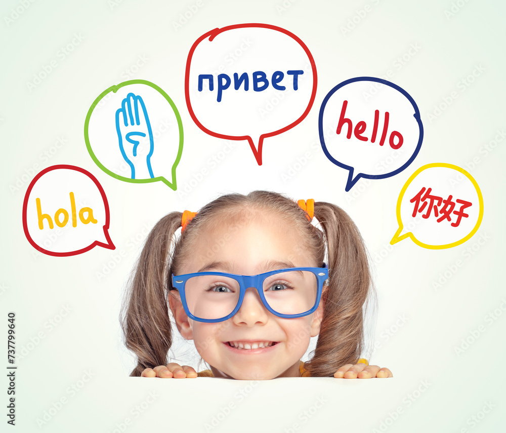 Little girl with eyeglasses leaning on table and looking at hello word