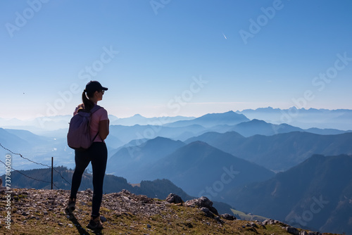 Active hiker woman looking at magical mountain peaks of Karawanks and Julian Alps seen from Goldeck, Latschur group, Gailtal Alps, Carintha, Austria. Mystical atmosphere in Austrian Alps in summer