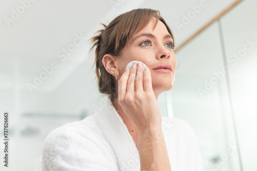 Caucasian middle-aged woman cleanses her face in a bright bathroom photo
