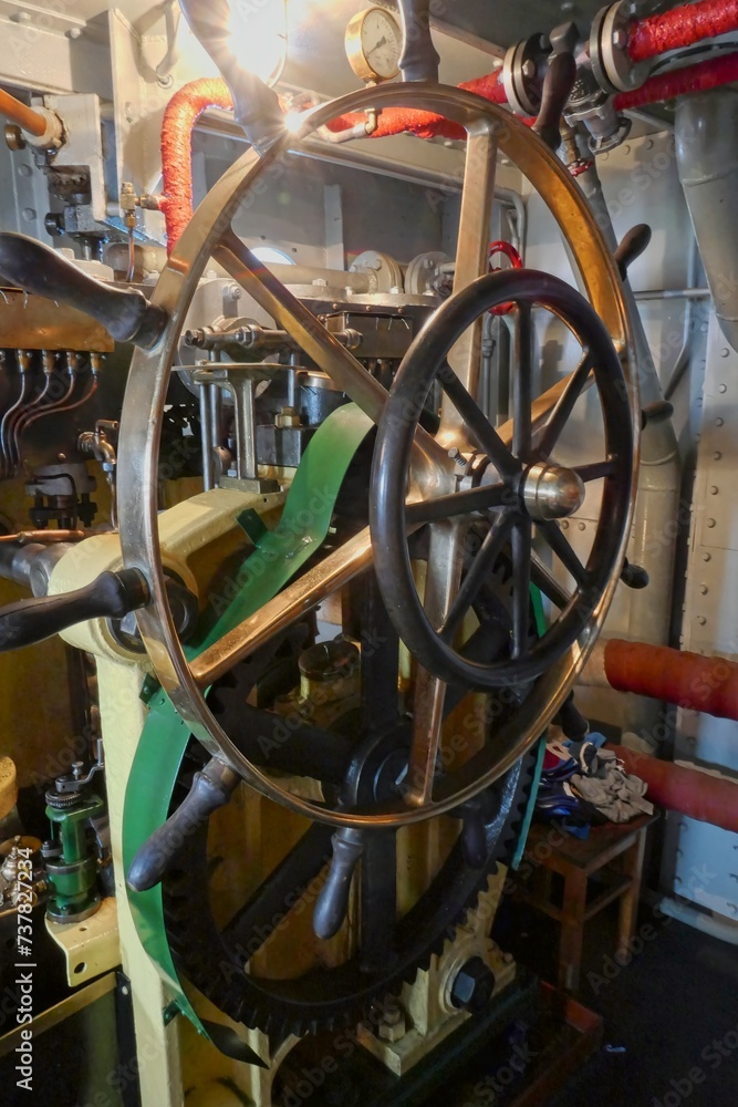 Metal steering wheel on an old steam ship inside.