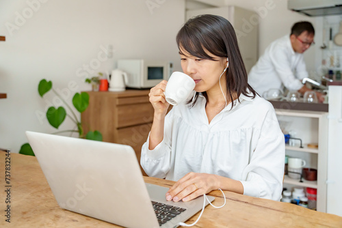 パソコンで仕事をする女性と家事をする男性 photo