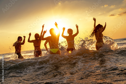 Happy young friends are having fun and runs to swim to sunset sea beach