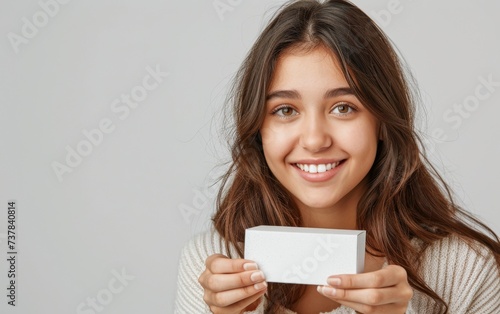 beautiful young girl presenting a small white box - product placement mockup