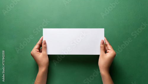 Female hands holding an empty white piece of paper with a green colorful background. Space for text, copy and other graphics. ai generated.