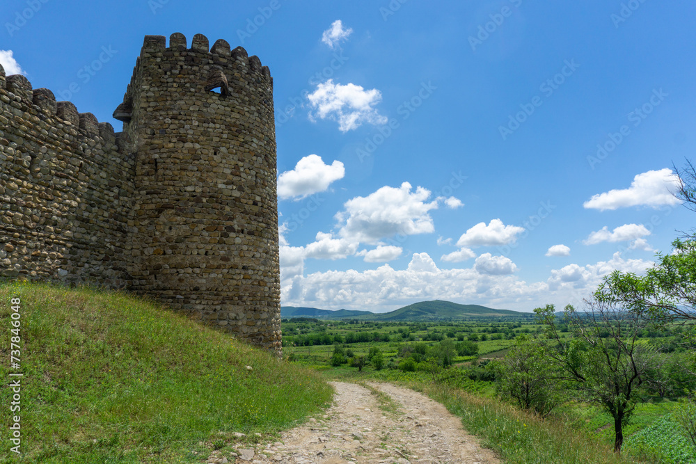 Medieval fortress wall and tower. Day light, blue sky and clouds. Georgia.