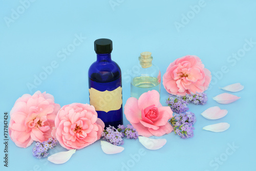 Rose and lavender flower aromatherapy essential oil with pink flowers on blue. Natural floral alternative healing medicine to treat skin conditions, insomnia, anxiety, promotes relaxation.