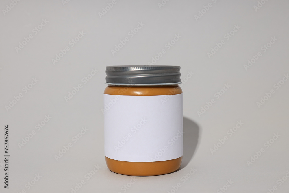 Peanut paste in a jar with a label, on a gray background. Peanut paste in a jar with a label, on a gray background.