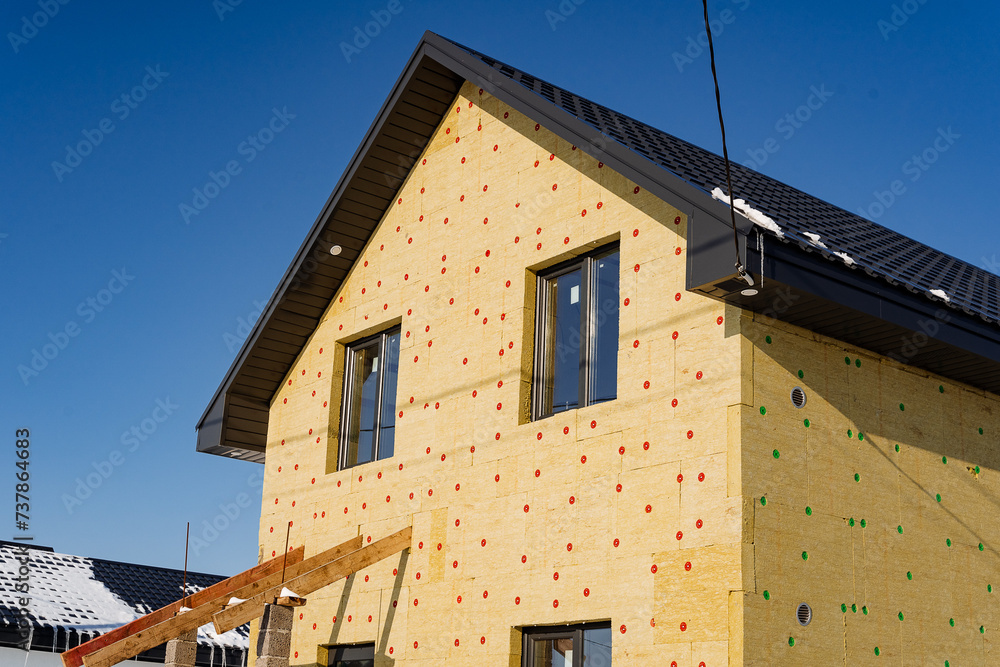 Insulation of the building with mineral wool, the country house is sheathed with insulation, installation of thermal panels, construction of the house.