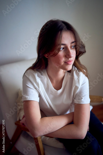portrait of a beautiful teenage girl on a chair in a bright room in a minimalist style
