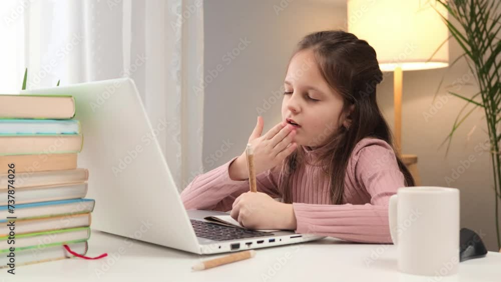 Remote education for school kids. Web-based learning at home. Child watching an online lecture. Caucasian little brown haired girl using laptop writing down task studying online at home Remote education for school kids. Web-based learning at home. Child watching an online lecture. Caucasian little brown haired girl using laptop writing down task studying online at home
