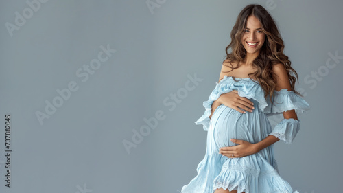 Hispanic pregnant woman with pregnancy belly, in soft blue clothes