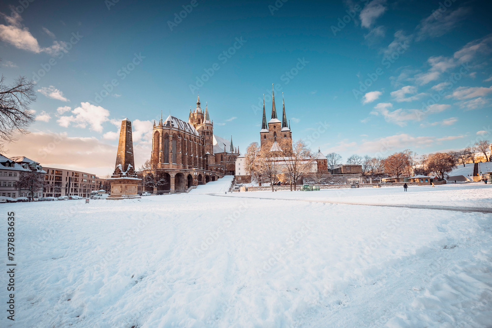 Obraz premium Der Erfurter Domplatz ist bedeckt von Schnee. In den frühen morgen Stunden, während des Sonnenaufgangs glänzte der Dom und St. Severi in strahlendem Licht, erhaben auf dem Domberg.