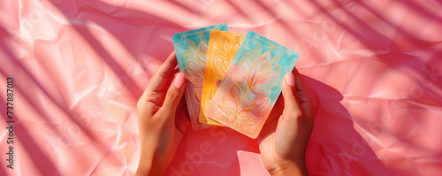 Hands holding 3 beautiful tarot and oracle card on pink background, inviting users to seek guidance, self-reflection, and spiritual insights. These cards serve as powerful tools for divination. photo