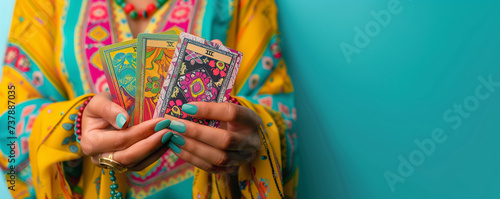 Woman holding tarot and oracle cards, on turquoise background, inviting users to seek guidance, self-reflection, and spiritual insights. These cards serve as powerful tools for divination.
